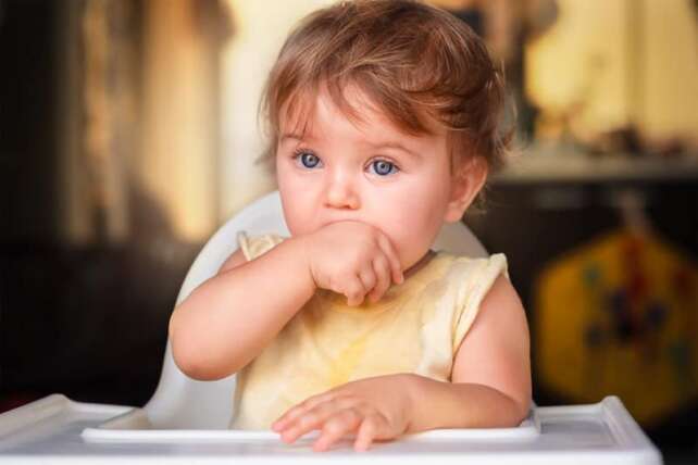 baby aggressively eating hands and crying